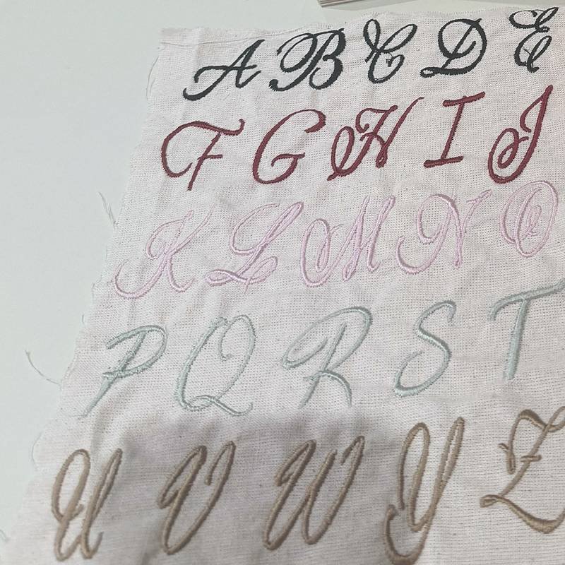 Abécédaire brodé en script sur coton écru, cinq couleurs de fil