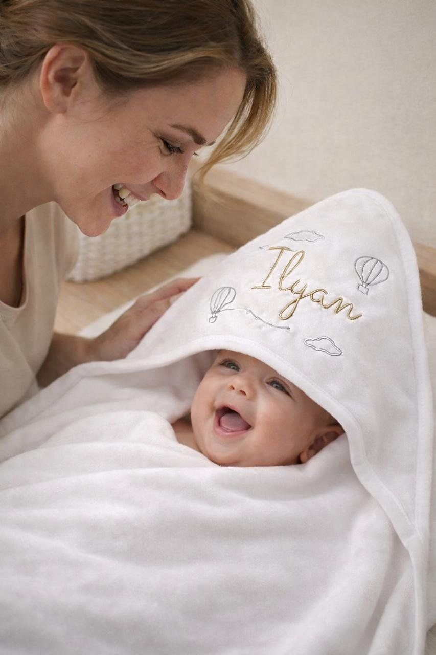 Bébé dans une cape de bain brodée à son prénom